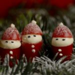Tre julemænd lavet af tomater på en baggrund af gran