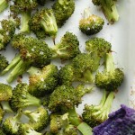 Frisklavet broccoli i ovn ligger i et hvidt fad sammen med en lilla grydelap