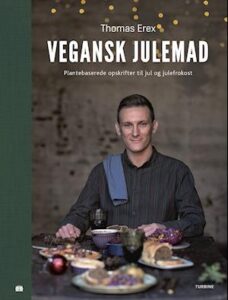 Thomas Erex ser i kameraet bagved et bord med vegansk julemad