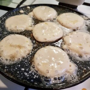 Æbleskivedej der ligger og steger i en æbleskivepande