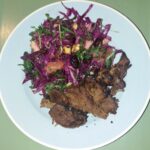 På en lyseblå tallerken ligger en smuk pink rødkålssalat samt kødlignende stykker af vegetarisk alternativ and også kaldet kaldet mock duck